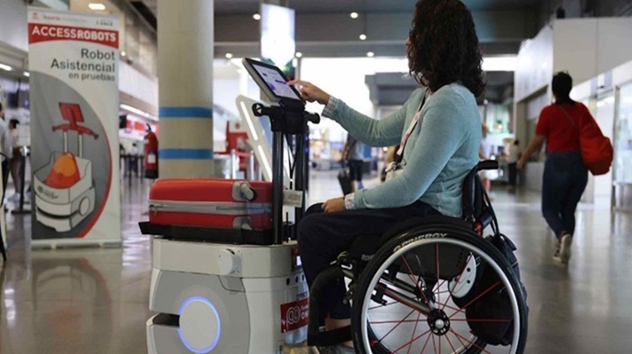 Una mujer que usa silla de ruedas interactúa con un robot de AccessRobots.