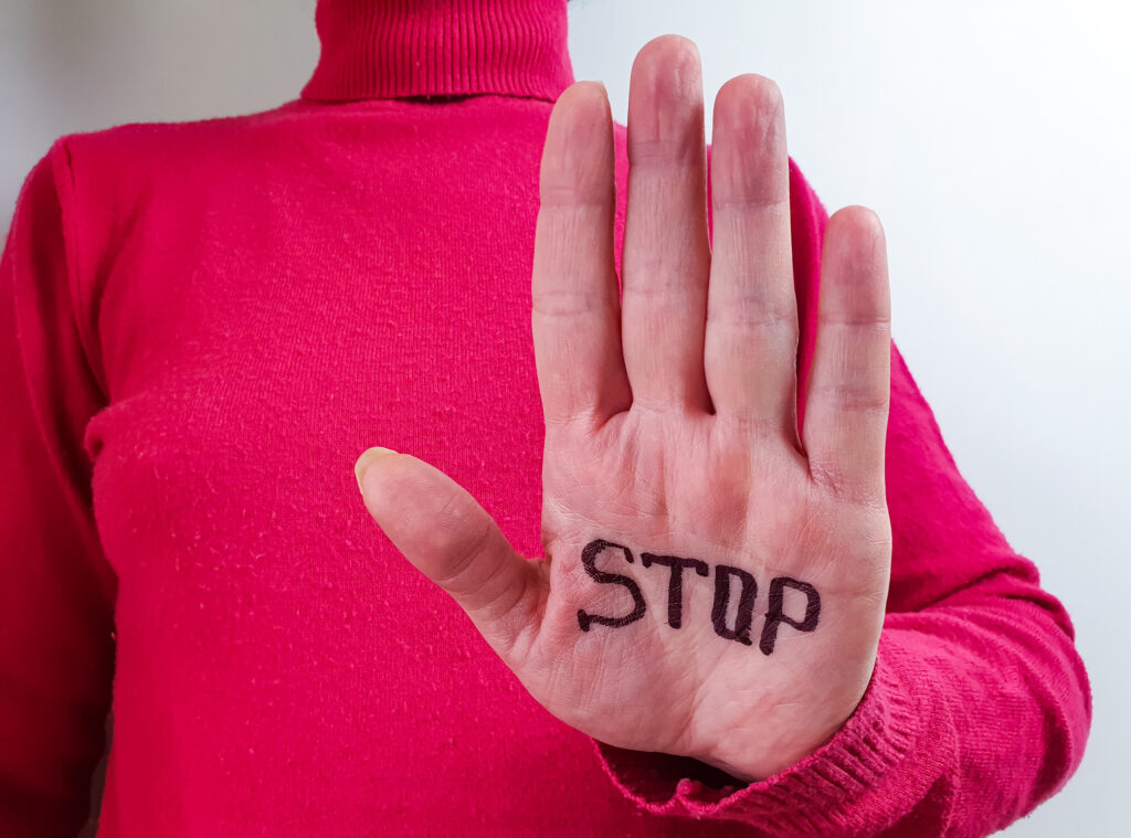 Una mujer muestra la palma de su mano donde tiene escrita la palabra Stop