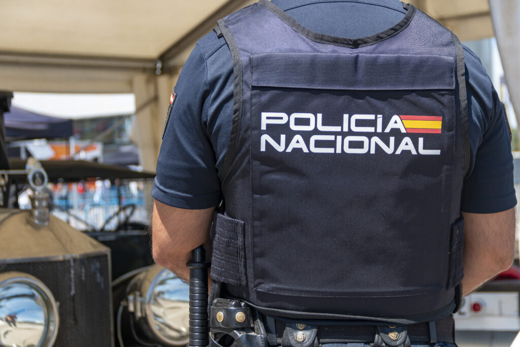 The back of a Spanish National police agent wearing a bulletproof vest where the name of the body is written.