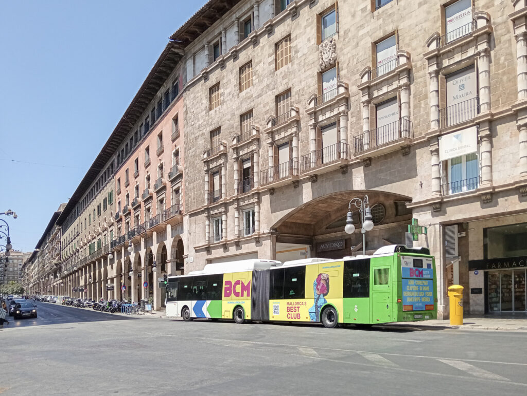 Autobús pasando delante de un edificio.
