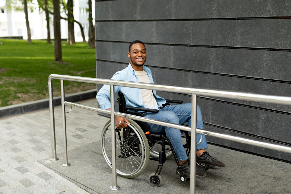 Persona en silla de ruedas subiendo una rampa accesible.