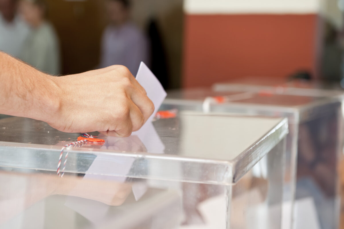 Mano depositando una papeleta en una urna